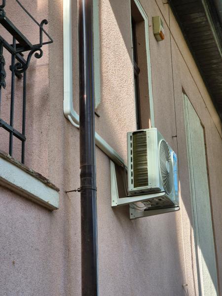 Kültéri egység fali konzolon, az ereszcsatorna mellett, rózsaszín vakolaton – klímaszerelés, Balázs Klíma